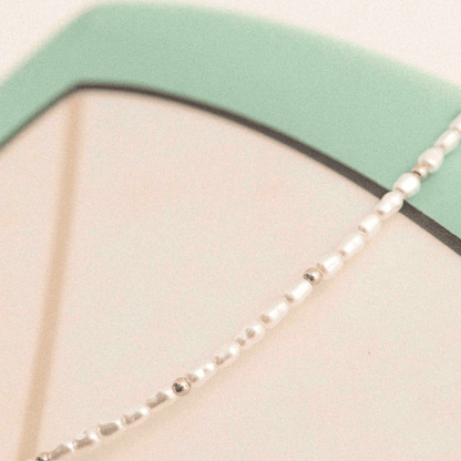 Detailaufnahme der Kette mit Imitationsperlen und goldfarbenem Glanz